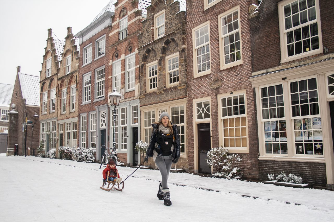 Hofstraat in de winter met kind op slee en sneeuw.